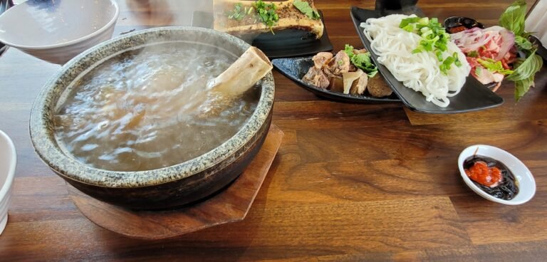 Steaming bowl of pho with broth, meat, and noodles, showcasing a traditional Vietnamese pho dish.