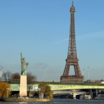 Daytime view of the Eiffel Tower seen from the Seine River with clear blue skies
