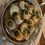 Traditional French escargot served in garlic butter with shells on a metal plate