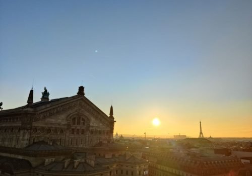 Sunrise over Paris with a view of Palais Garnier and the Eiffel Tower in the distance.